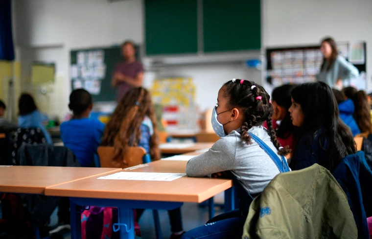 A girl wears a face mask as students sit in a classroom of the Petri primary school in Dortmund, western Germany, on June 15, 2020, amid the novel coronavirus COVID-19 pandemic. | AFP via Getty Images/Ina Fassbender