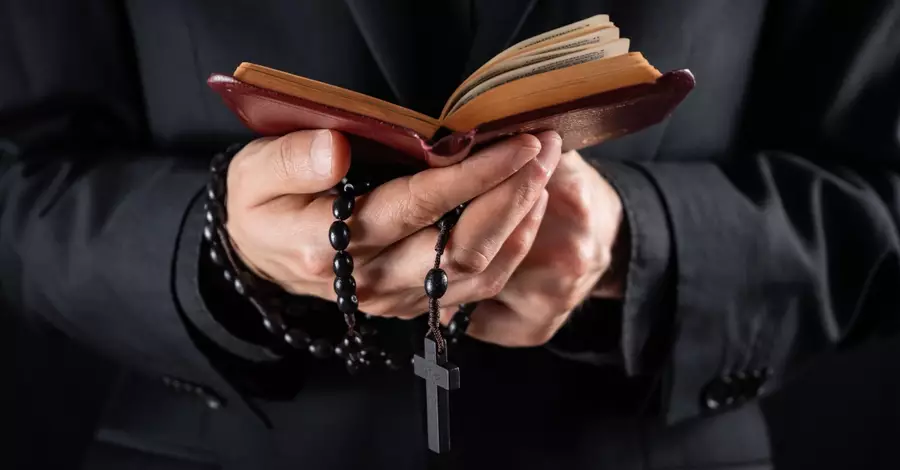 priest carrying a bible with open palms and rosary