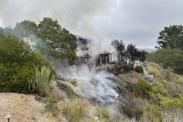 In this photo provided by the Monterey County Regional Fire District is the scene where a plane crashed into a home near Highway 68 in Monterey County, Calif., on Tuesday, July 13, 2021. A small plane crashed into a home starting a fire in the house that spread to nearby wild land. It is not yet known if people were inside the residence or how many people were on the plane, an official said. The twin-engine Cessna 421 crashed into a residential area after departing from the Monterey Regional Airport in Monterey, Calif. (Monterey County Regional Fire District via AP)