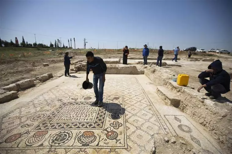 A worker for the Israel Antiquities Authority stands on the mosaic floor of a monastery unearthed during excavations